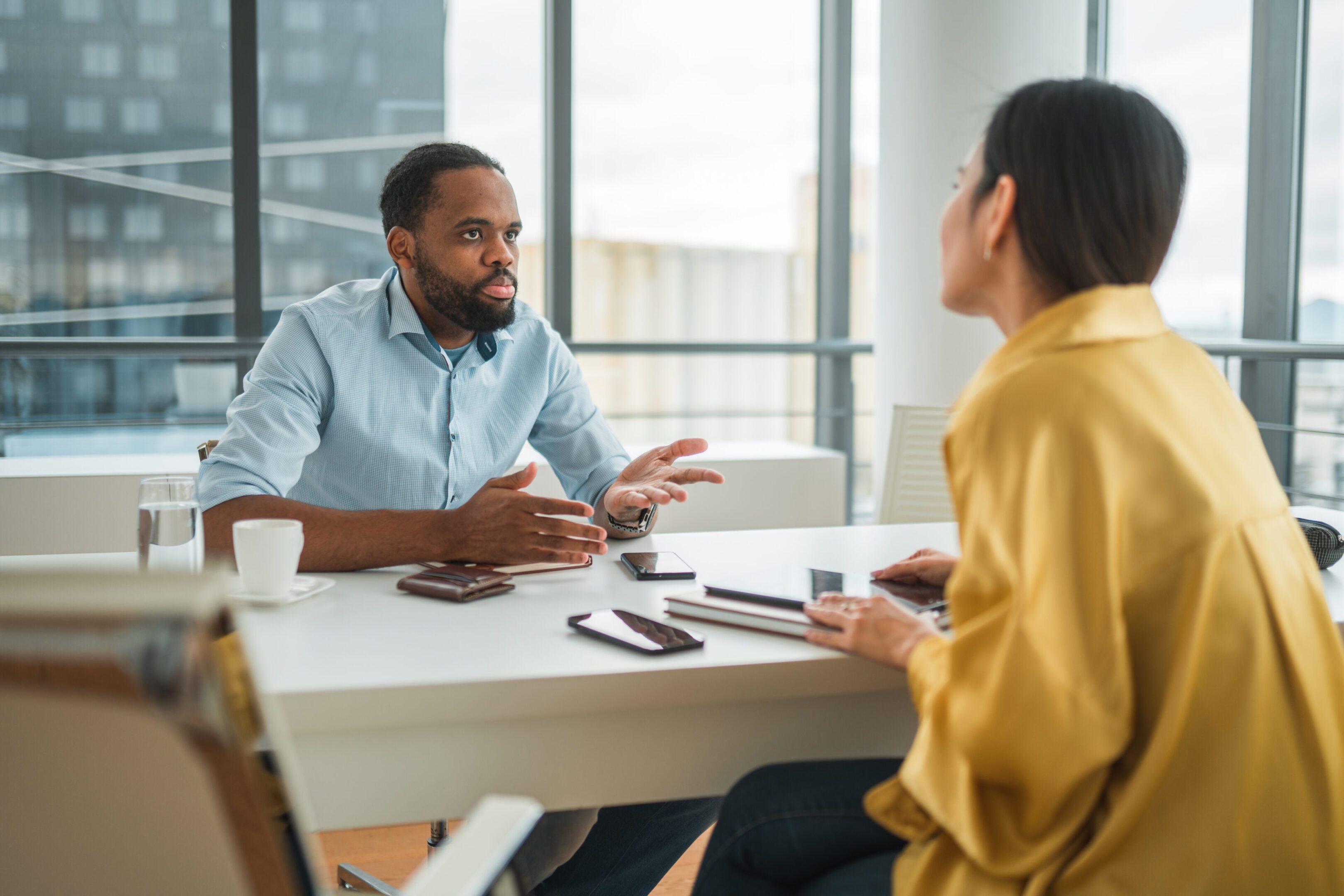 Two colleagues discussing work at a modern office desk.